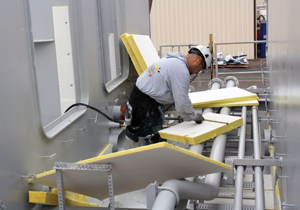 A man wearing a hard hat is working on a building