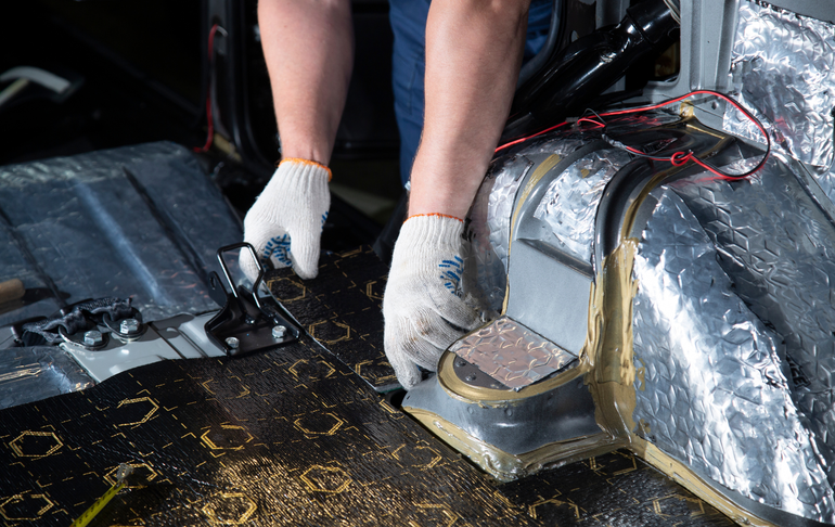 A person is working on a car with a pair of scissors.