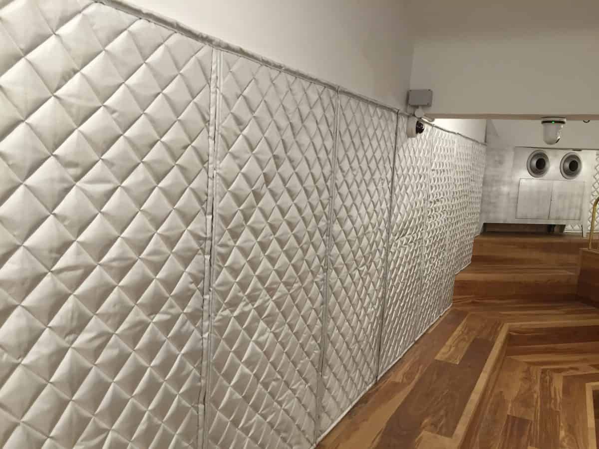 A white quilted wall with a wooden floor in a room.