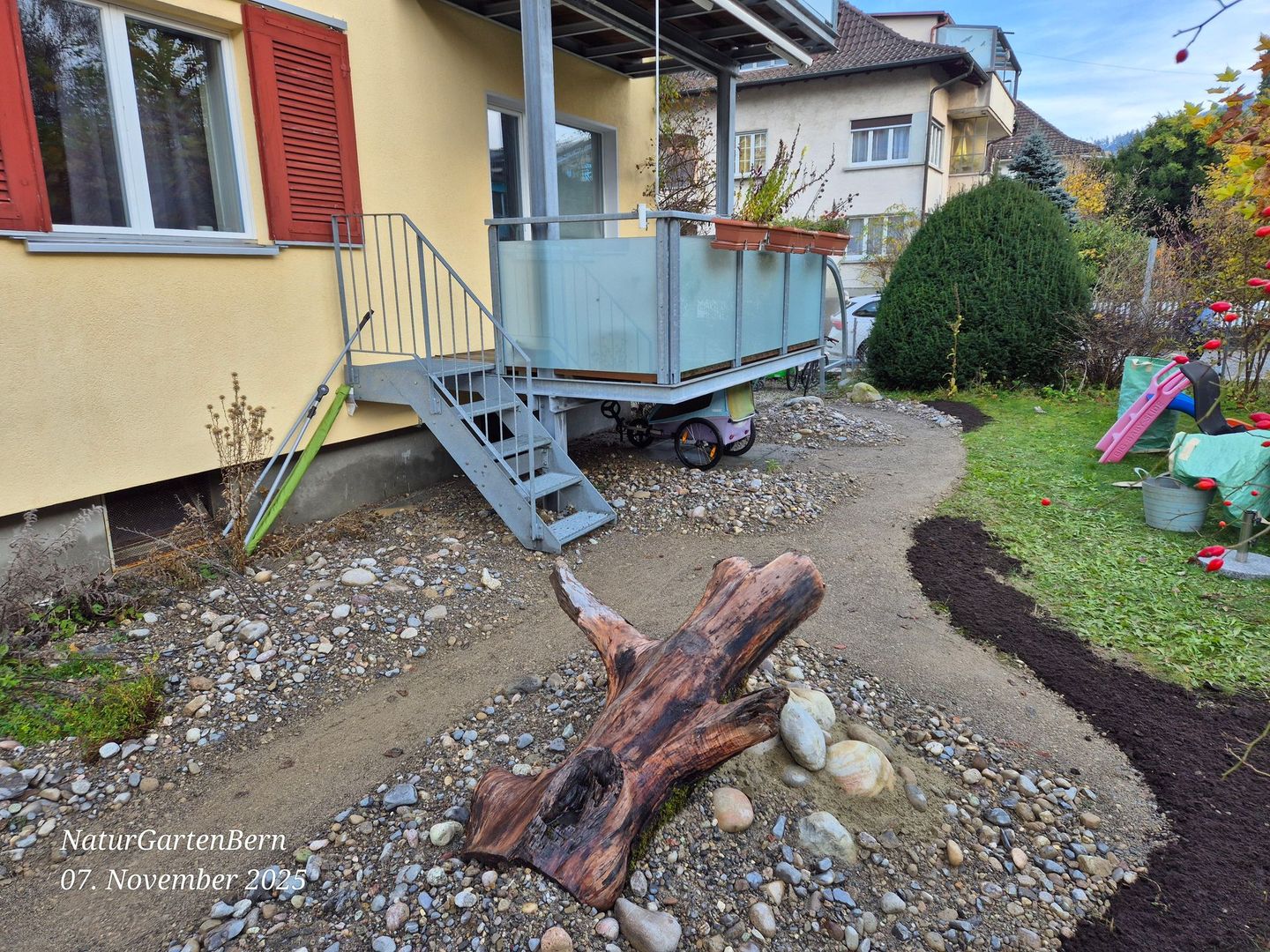 Trockenbiotop bei einem Mehrfamilienhaus in Köniz, mit Totholz und Sandarium für Wildbienen.