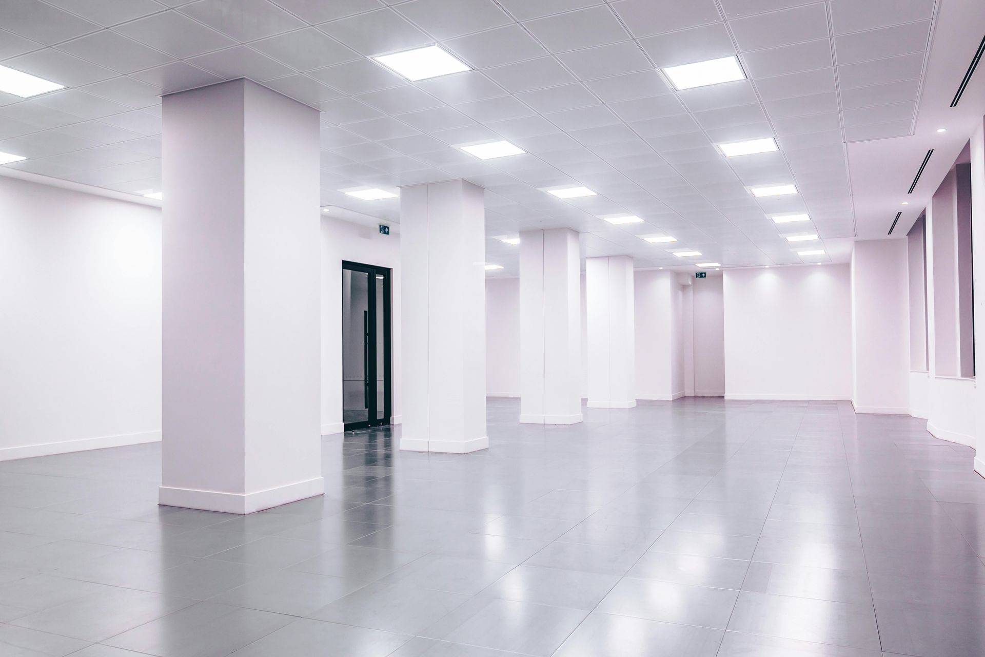 Empty, brightly lit white interior with columns and a reflective gray floor.
