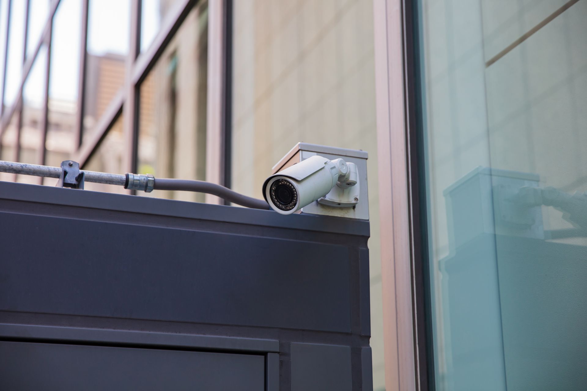 Security camera mounted on a building exterior, angled towards a walkway.