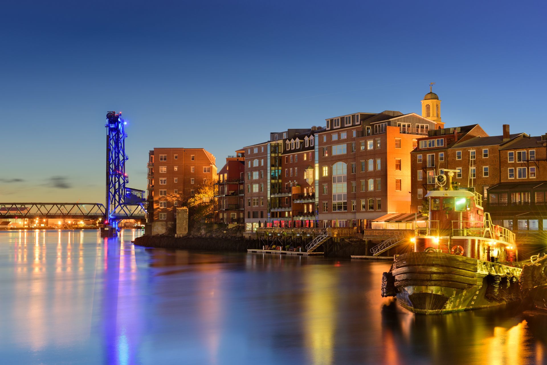 A city at night with a bridge over a body of water.