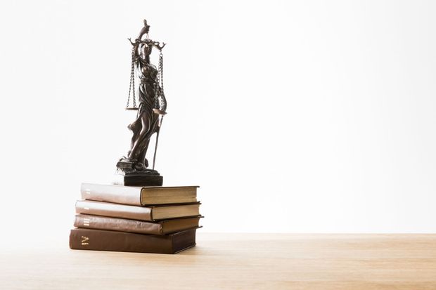 Bronze statuette atop a stack of books on a wooden surface against a white background