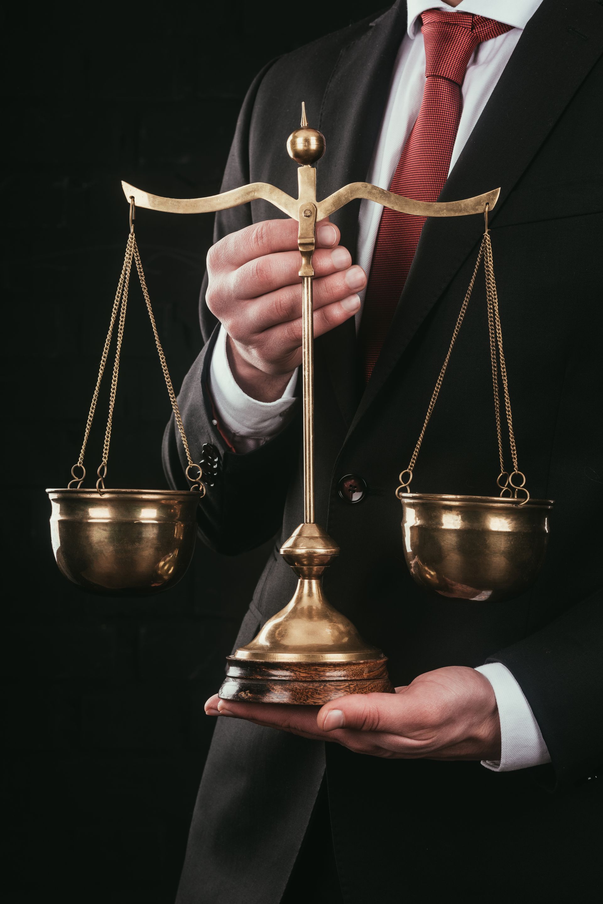 A man in a suit and tie is holding a scale of justice in his hands.