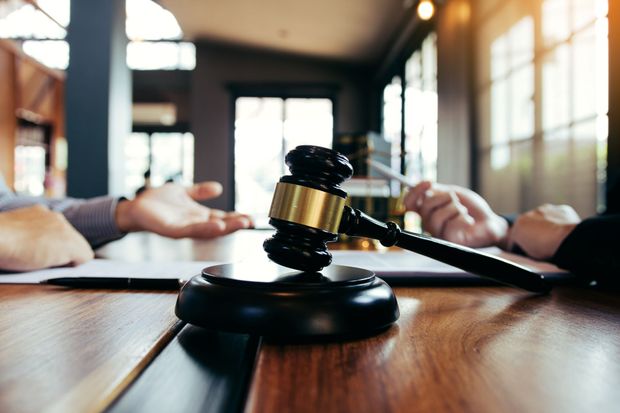 Gavel on a conference table with people in a blurred meeting room background