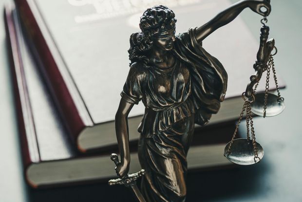Bronze Lady Justice statue holding scales and sword beside an open law book