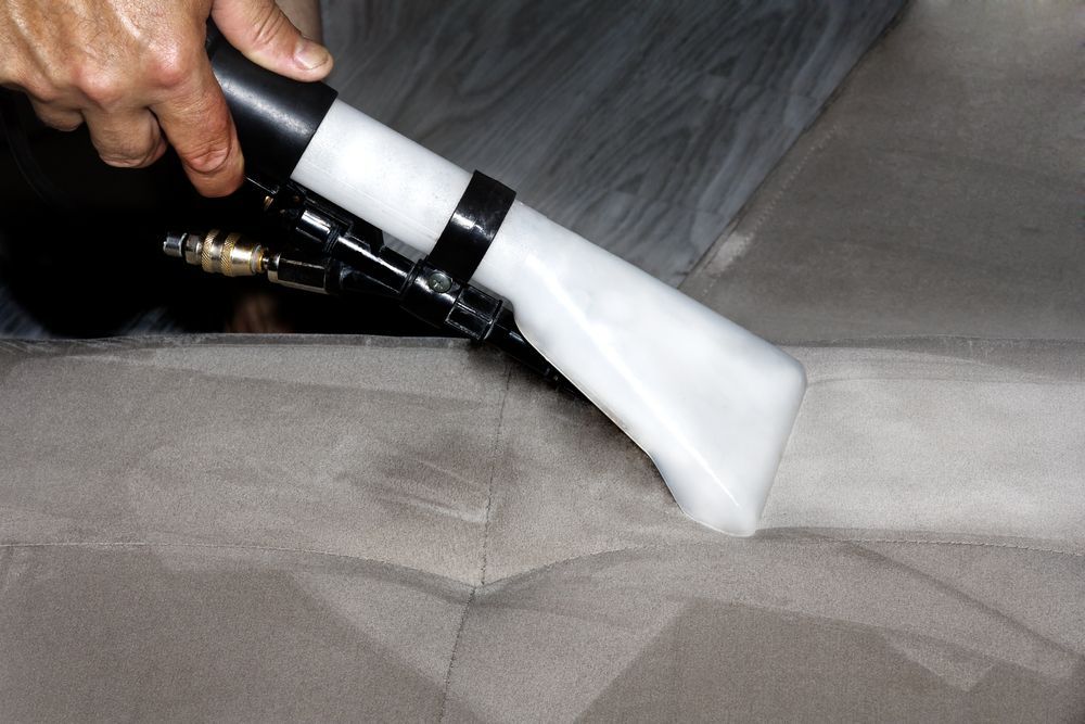 Person Using Upholstery Cleaning Tool on a Grey Sofa — Chemdry D & K in Geelong, VIC