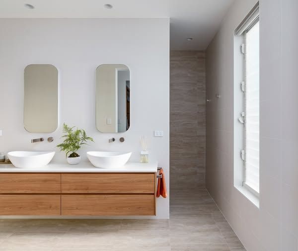 Modern Bathroom With Double Sinks, Wooden Vanity, Mirrors, and a Large Window — DSR Plumbing Pty Ltd in Ashtonfield, NSW