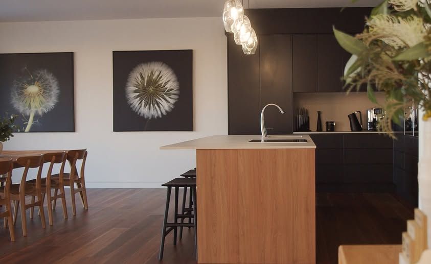 Modern Kitchen and Dining Area With a Wooden Island, Dark Cabinets, Pendant — DSR Plumbing Pty Ltd in Ashtonfield, NSW