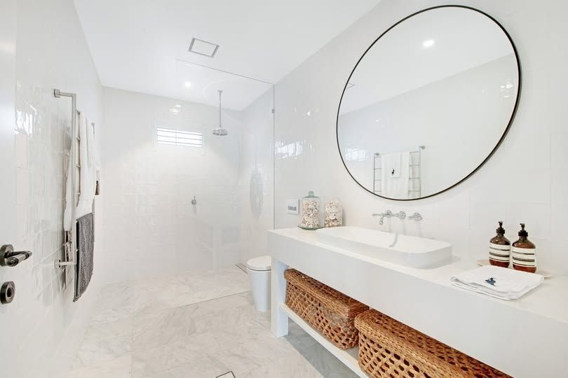 Bright White Modern Bathroom with Large Round Mirror, Double Sinks, and Walk-In Shower — DSR Plumbing Pty Ltd in Cessnock, NSW