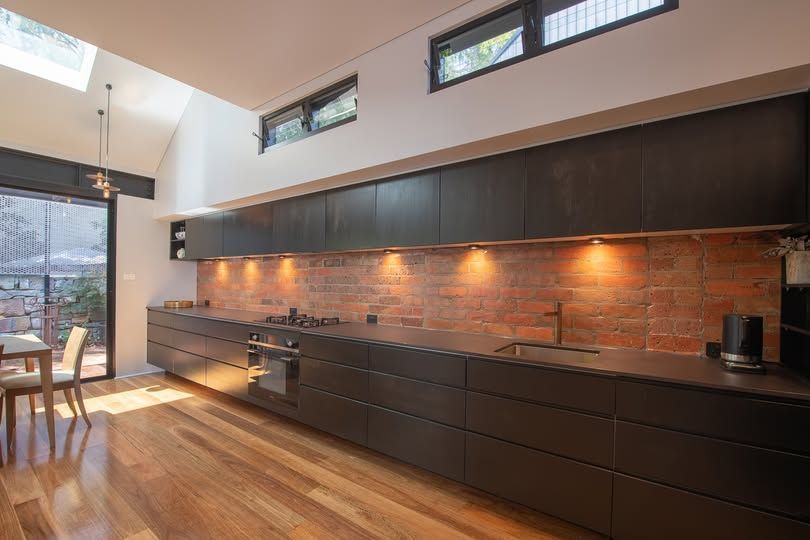 Modern Kitchen With Dark Cabinets, Brick Backsplash, Wood Floors — DSR Plumbing Pty Ltd in Ashtonfield, NSW