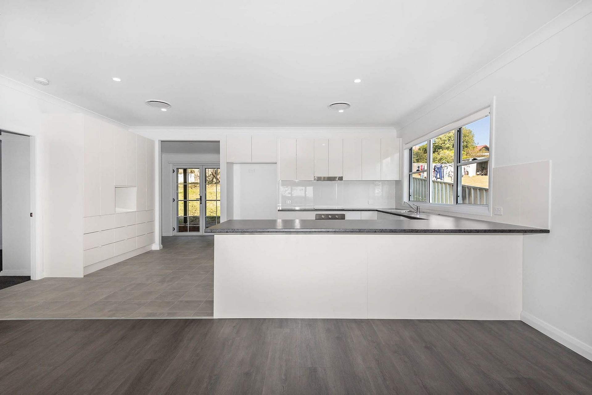 Bright White Modern Kitchen With Gray Flooring, Large Island — DSR Plumbing Pty Ltd in Ashtonfield, NSW