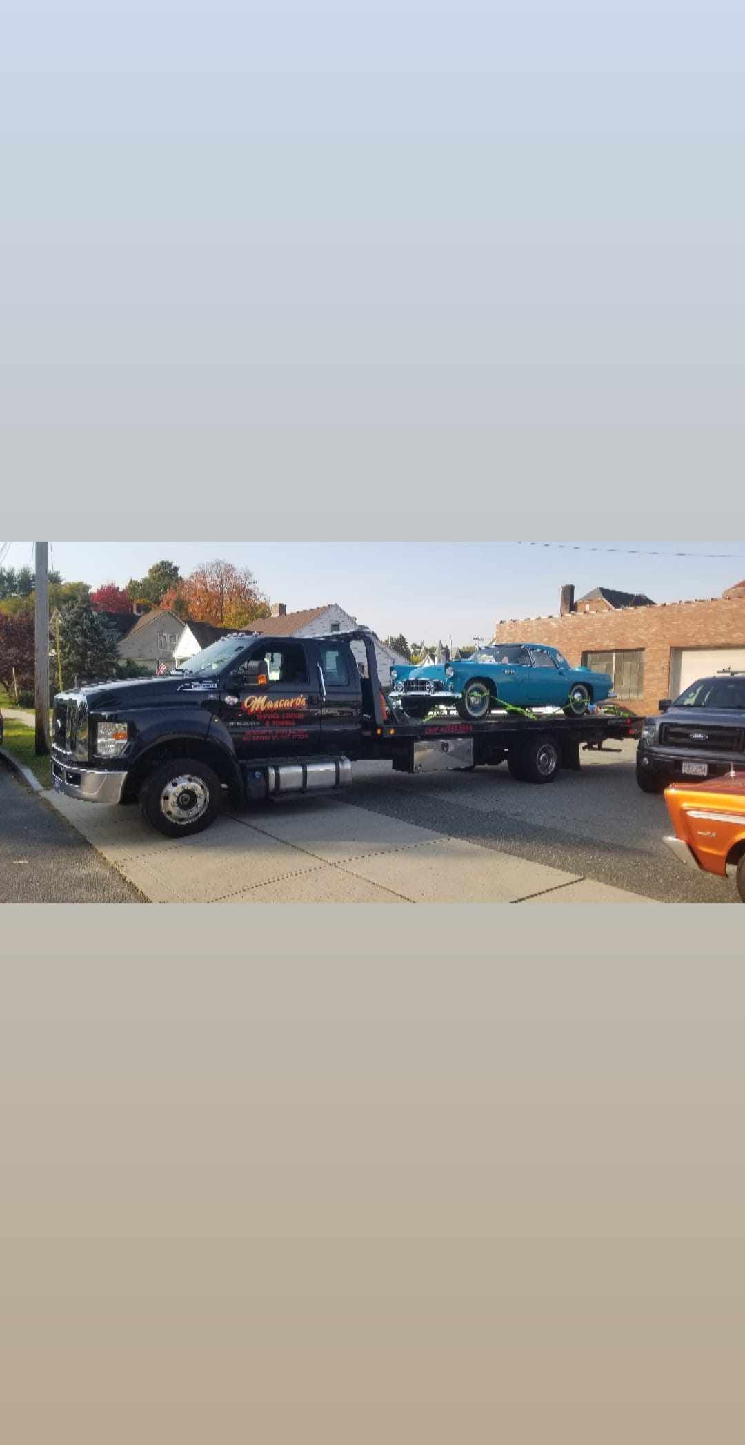 A tow truck is towing a car in a parking lot.