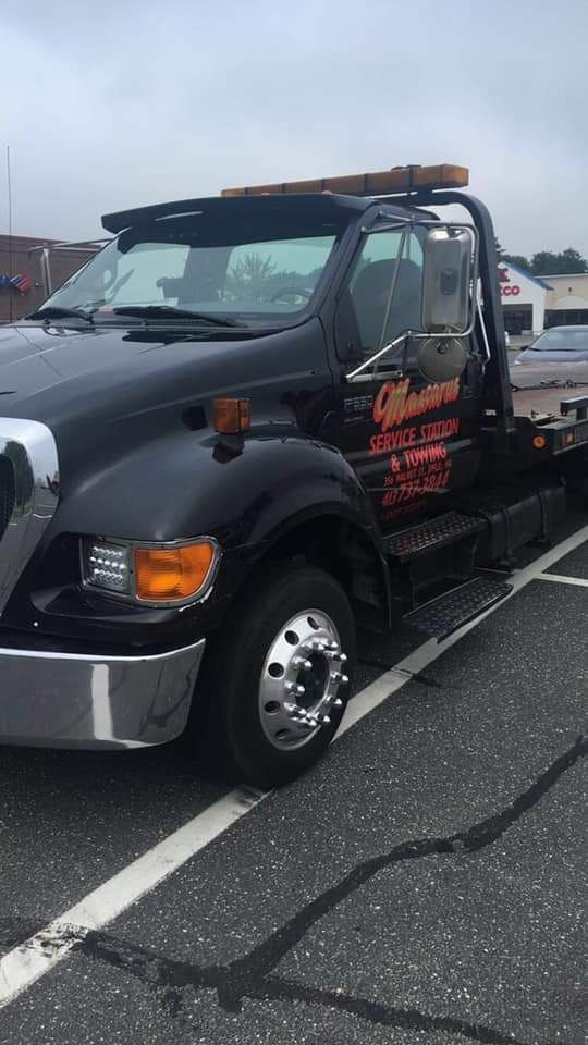 A black tow truck is parked in a parking lot.