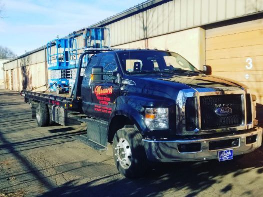 A tow truck with a lift on the back is parked in front of a building.