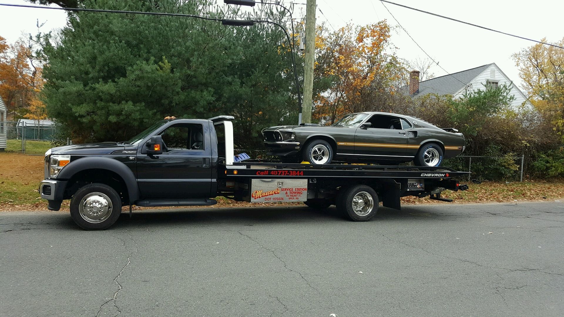 A tow truck is carrying a mustang on the back of it.