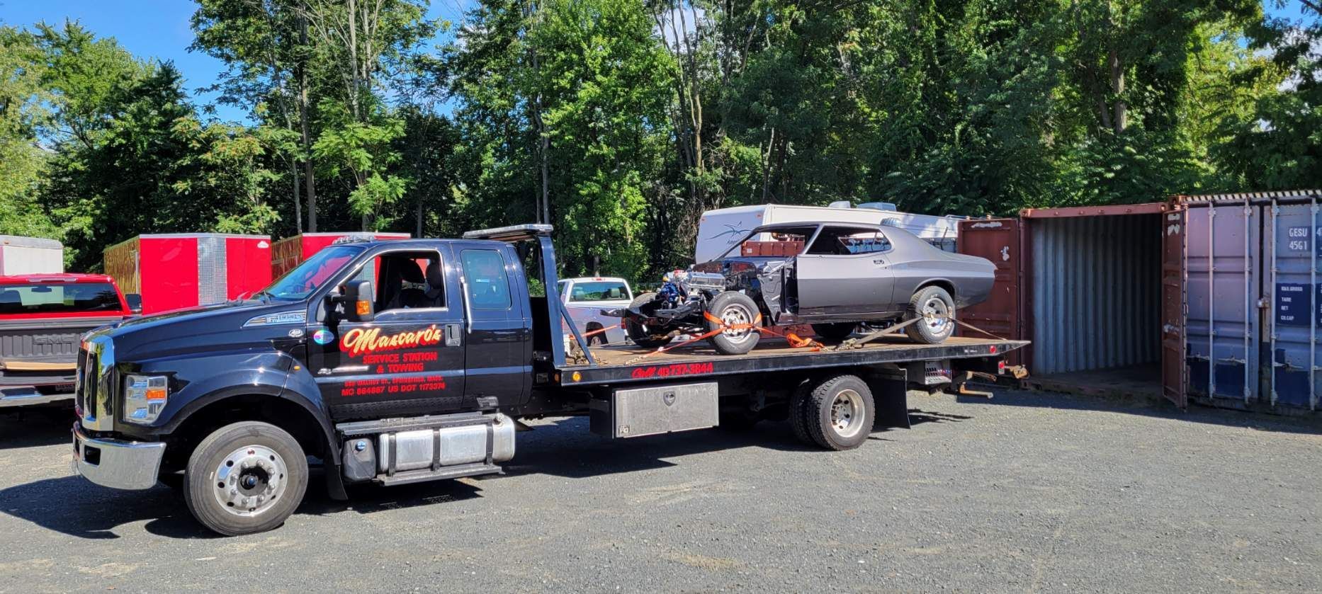 A tow truck is carrying a car on the back of it.
