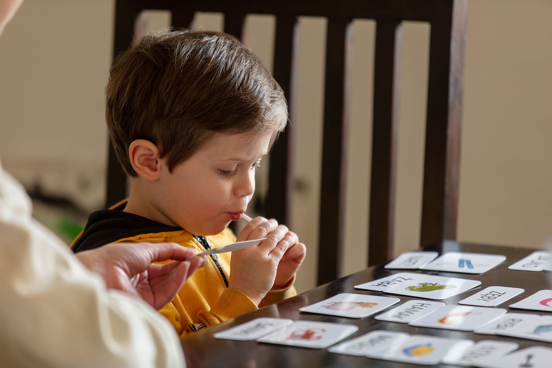 A young boy is sitting at a table playing a game of cards.