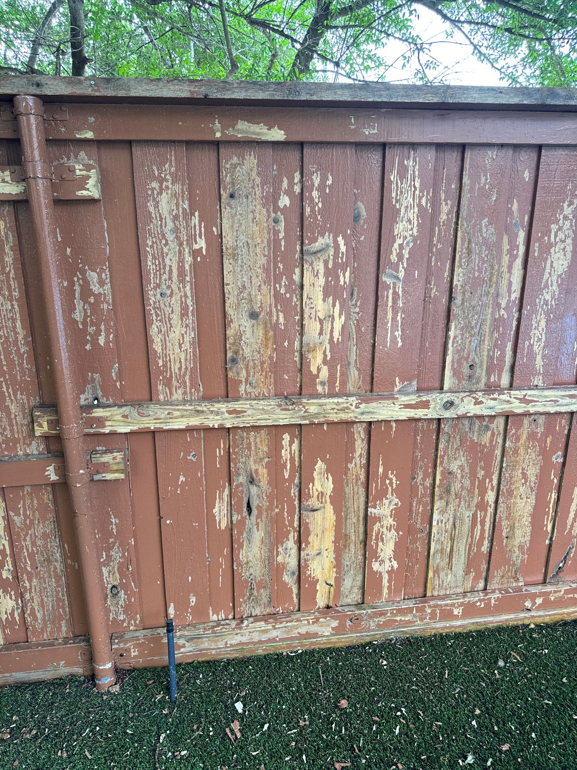 Brown wooden fence with peeling paint, outdoors.