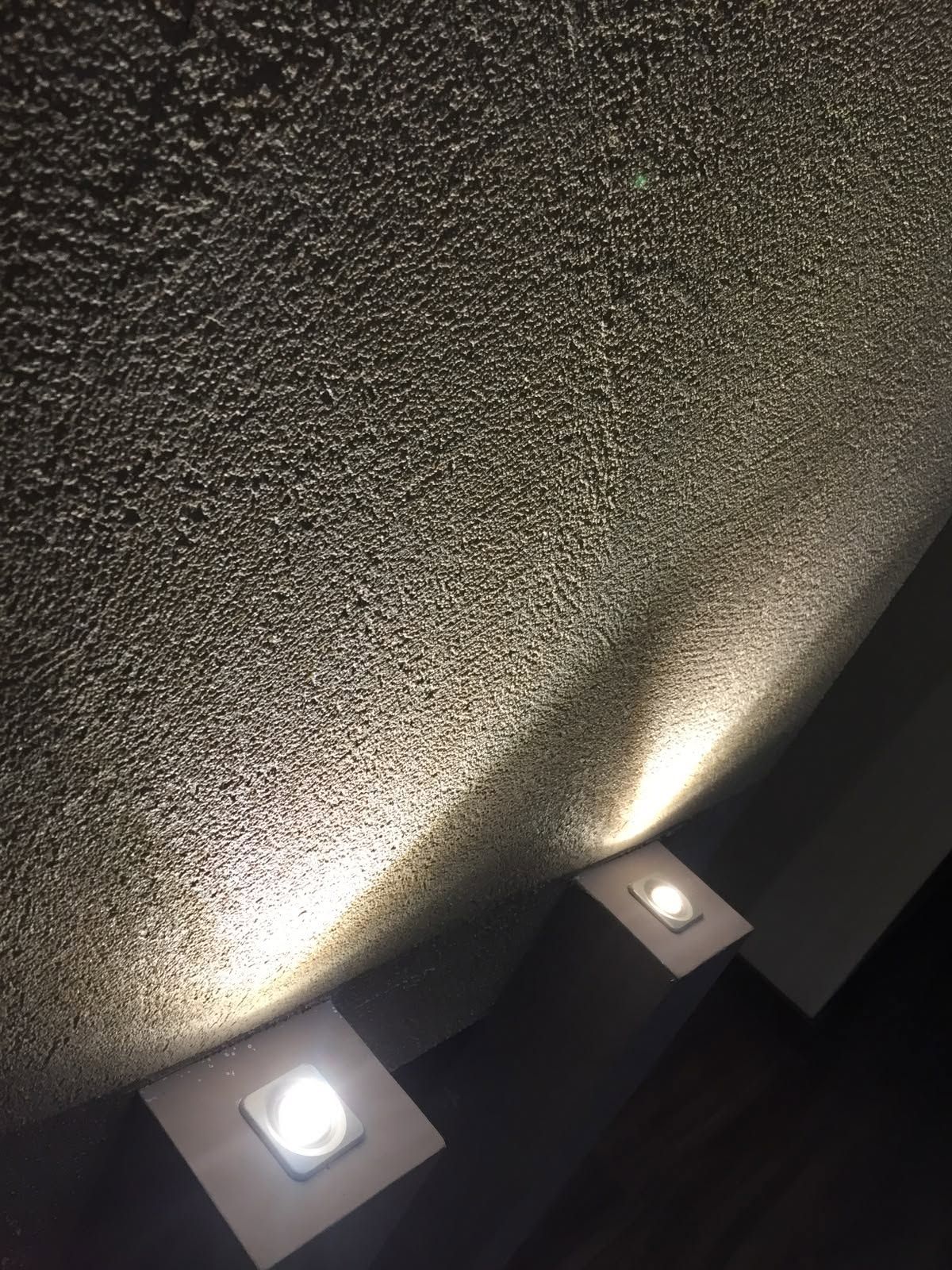 Due plafoniere accese su un soffitto ruvido in una stanza poco illuminata