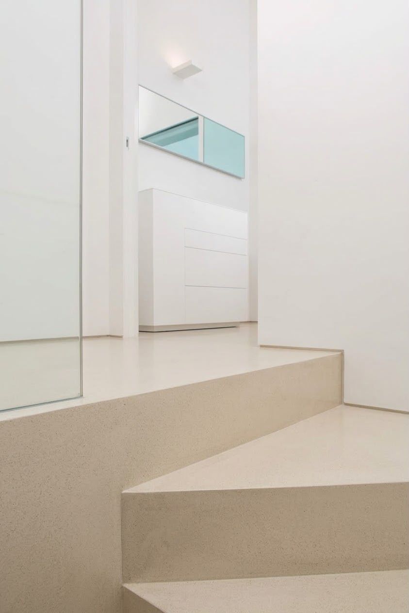 Interno minimalista bianco con una pedana beige a gradini e pannelli a specchio alle pareti
