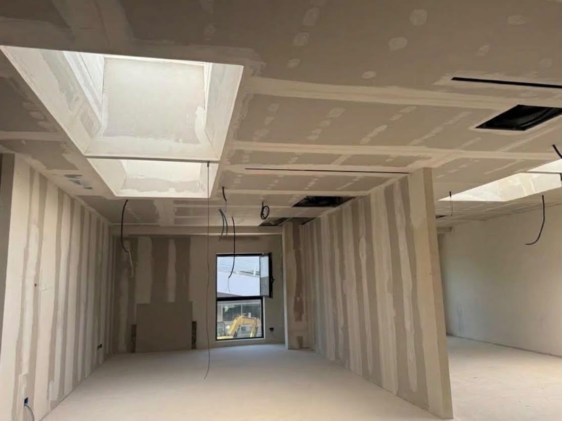 Stanza incompiuta in costruzione, con cartongesso a vista, aperture nel soffitto e una finestra in fondo