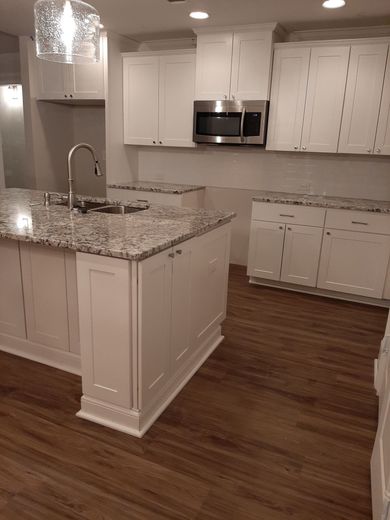 A kitchen under construction with white cabinets and a large island.