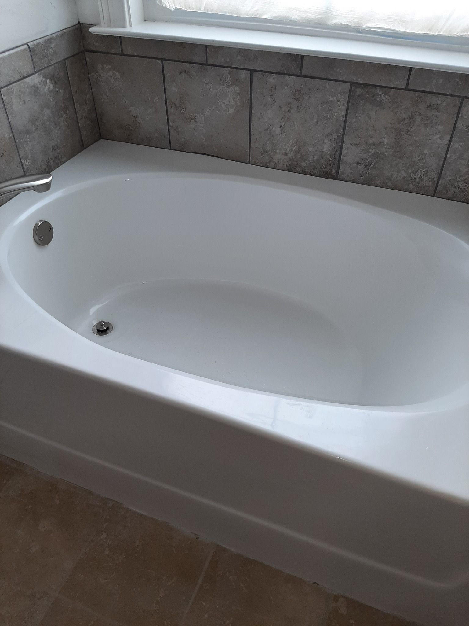 A white bathtub in a bathroom next to a window.