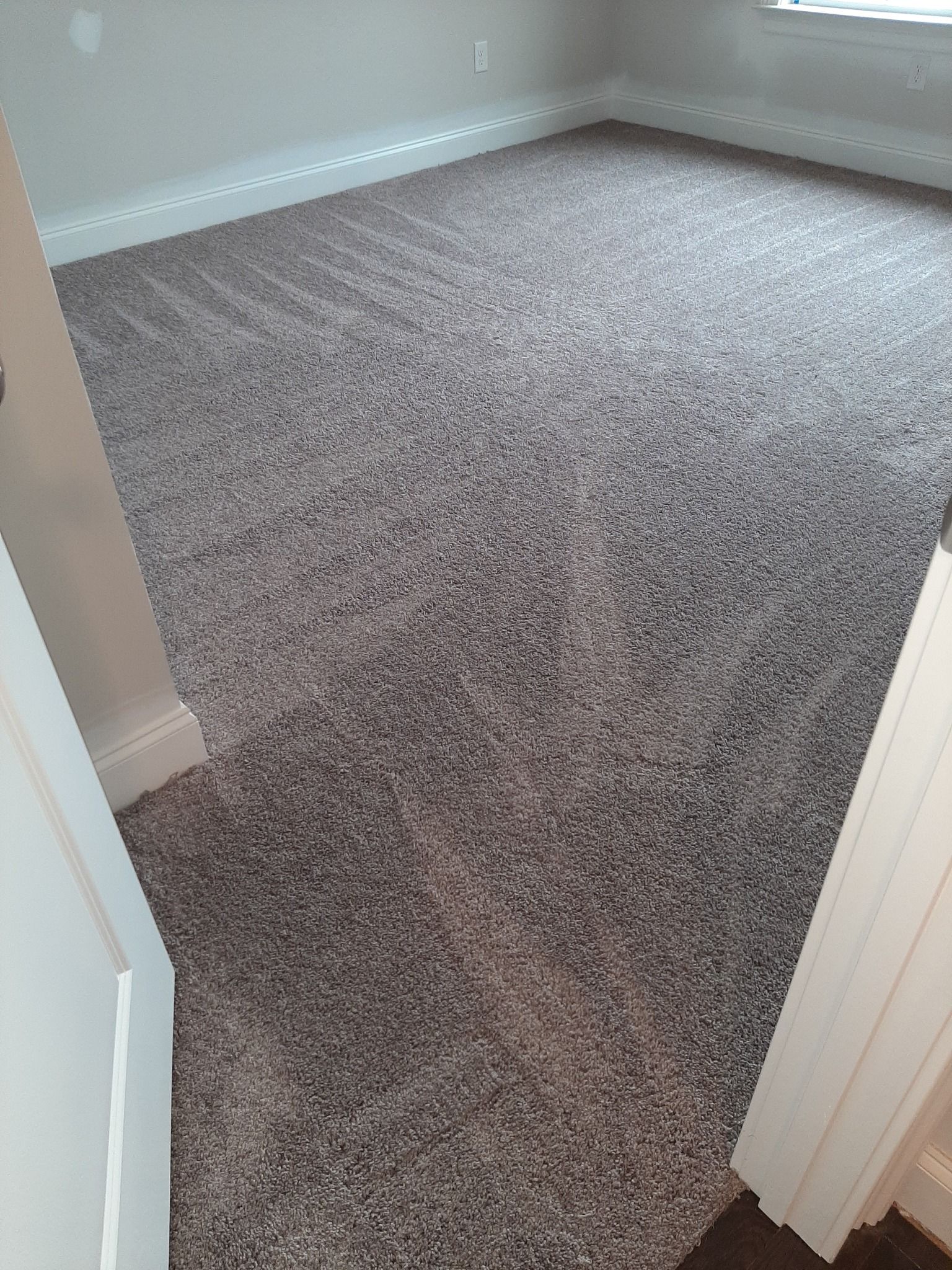 A bedroom with a large carpeted floor and a window.