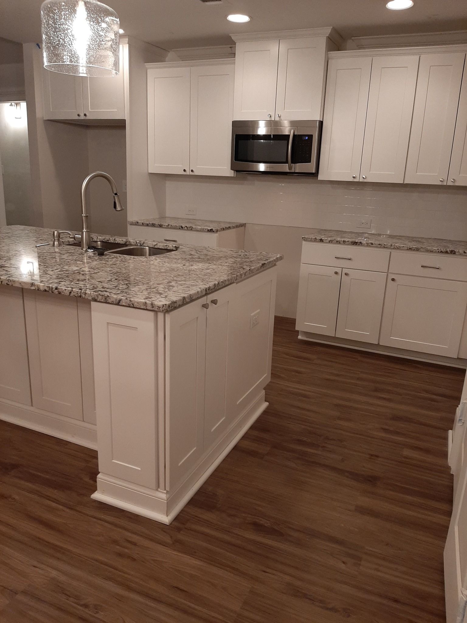 A kitchen with granite counter tops and white cabinets