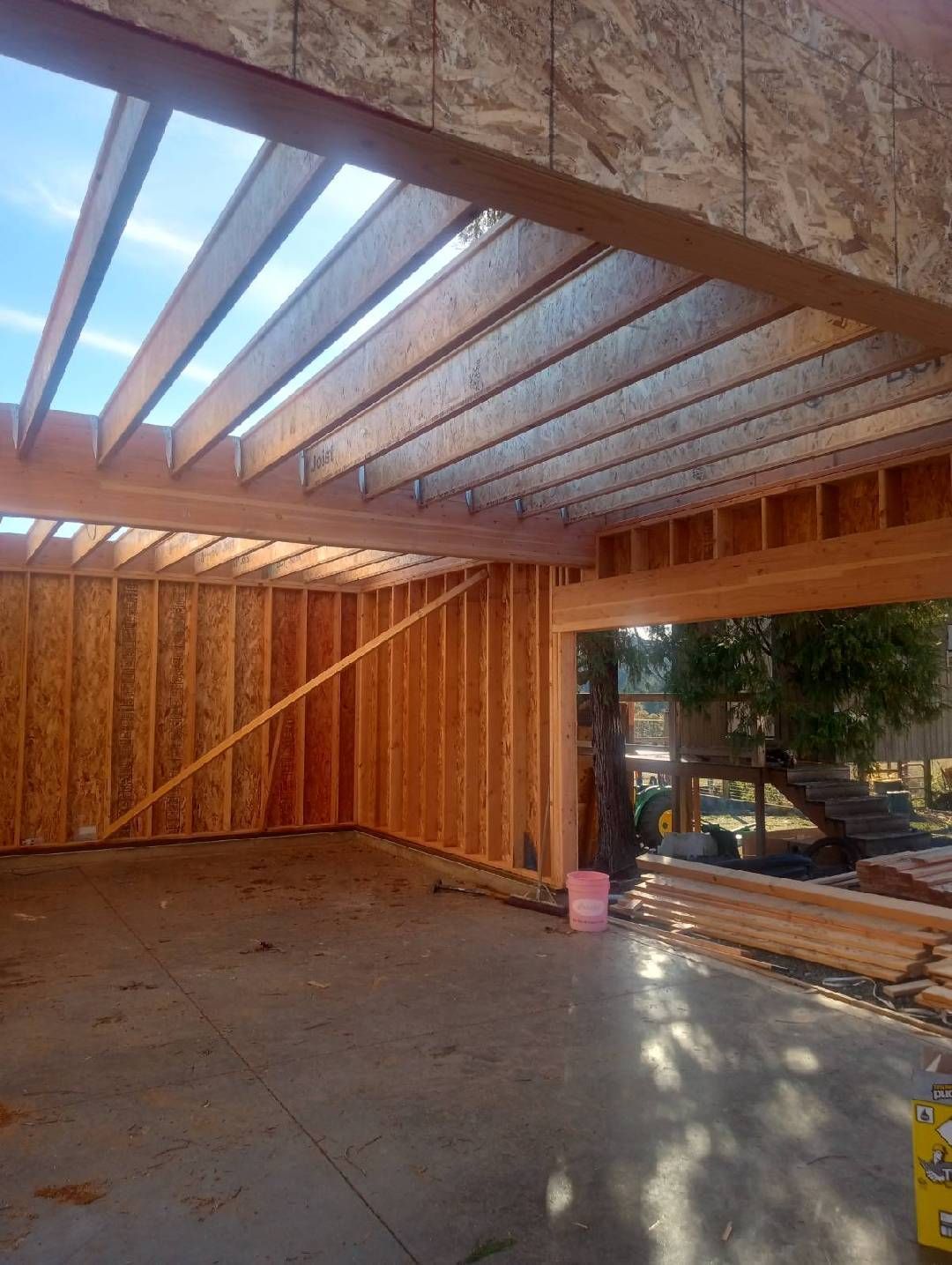 Interior of a wooden-framed garage under construction with skylight openings and a concrete floor