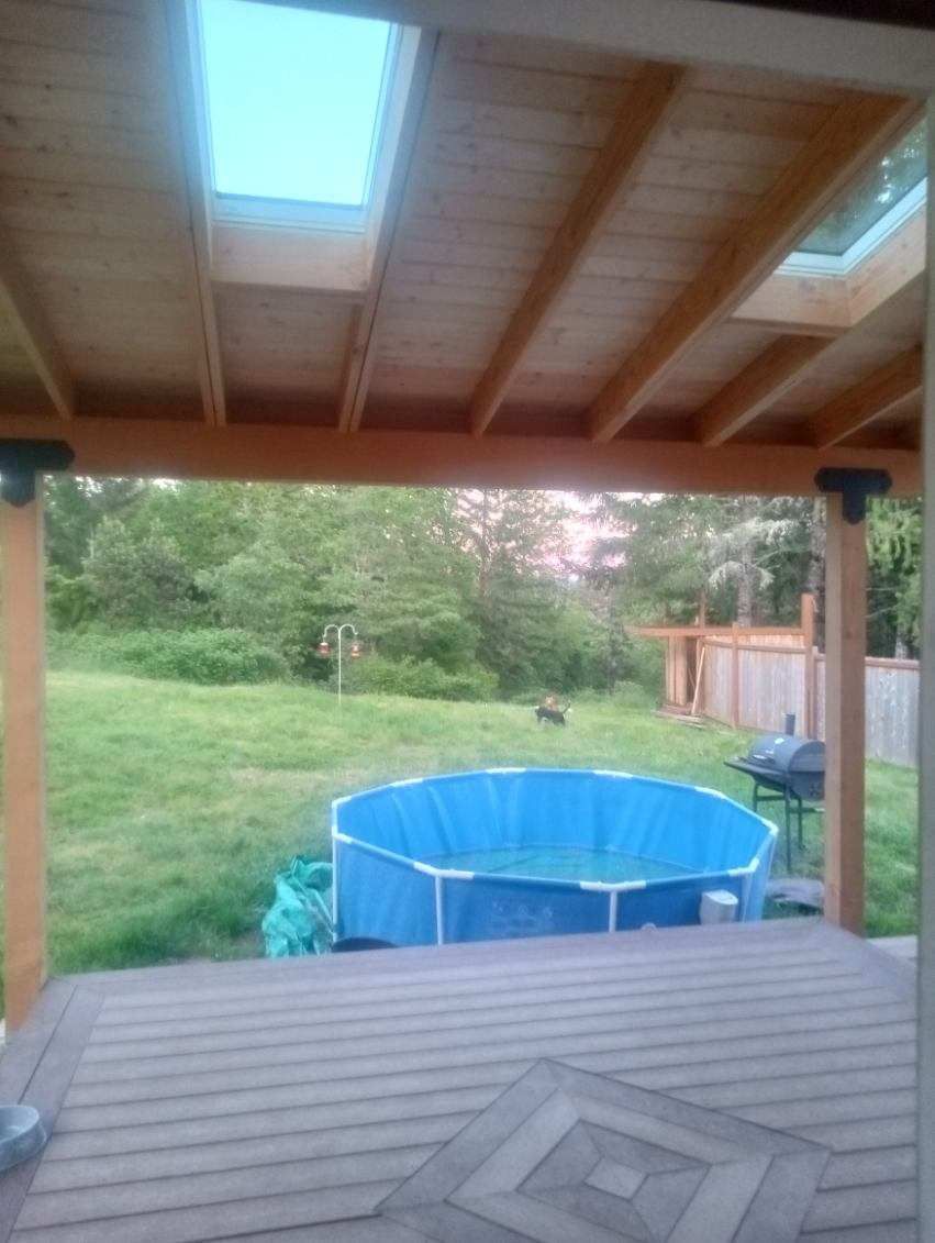 Covered deck overlooking backyard with a blue above-ground pool and grassy lawn