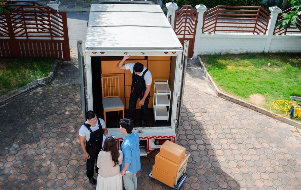 Moving Crew Loading Boxes And Furniture Into A Truck In Front Of A House