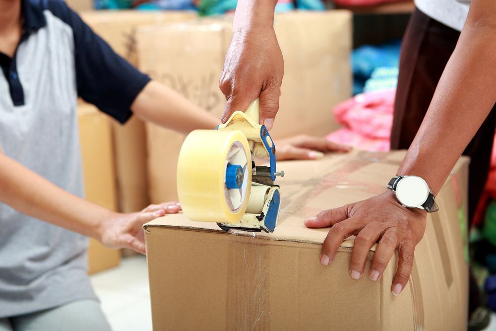 Two People Sealing a Cardboard Box With Packing Tape — Lite Moves Furniture Removals In Sydney, NSW