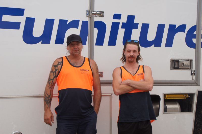 Two workers in orange standing in front of a white truck — Lite Moves Furniture Removals In Bonville, NSW