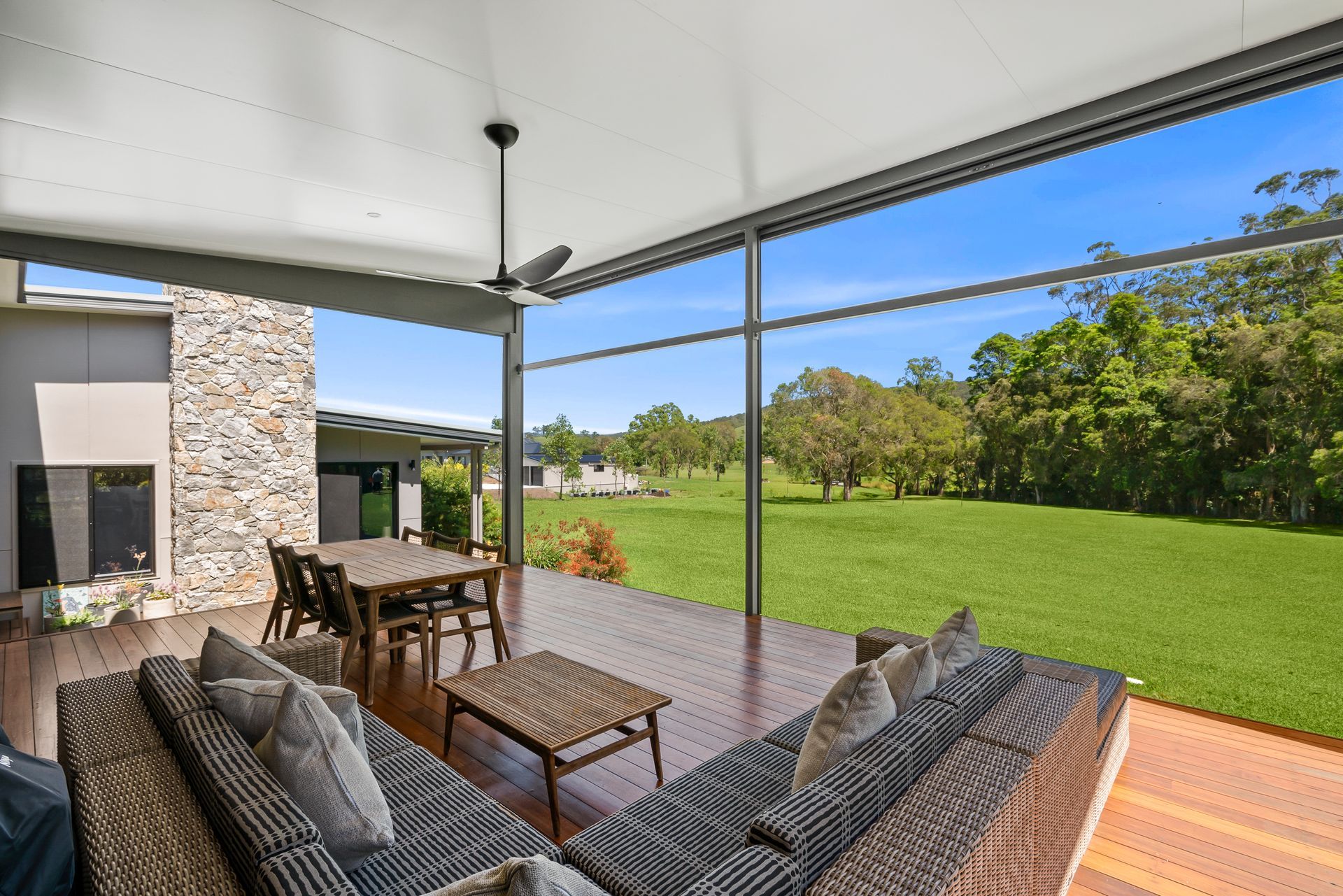 A corner view of an outdoor area with a table and a couch set and lawn in front of it — PK4 Projects in Port Macquarie, NSW