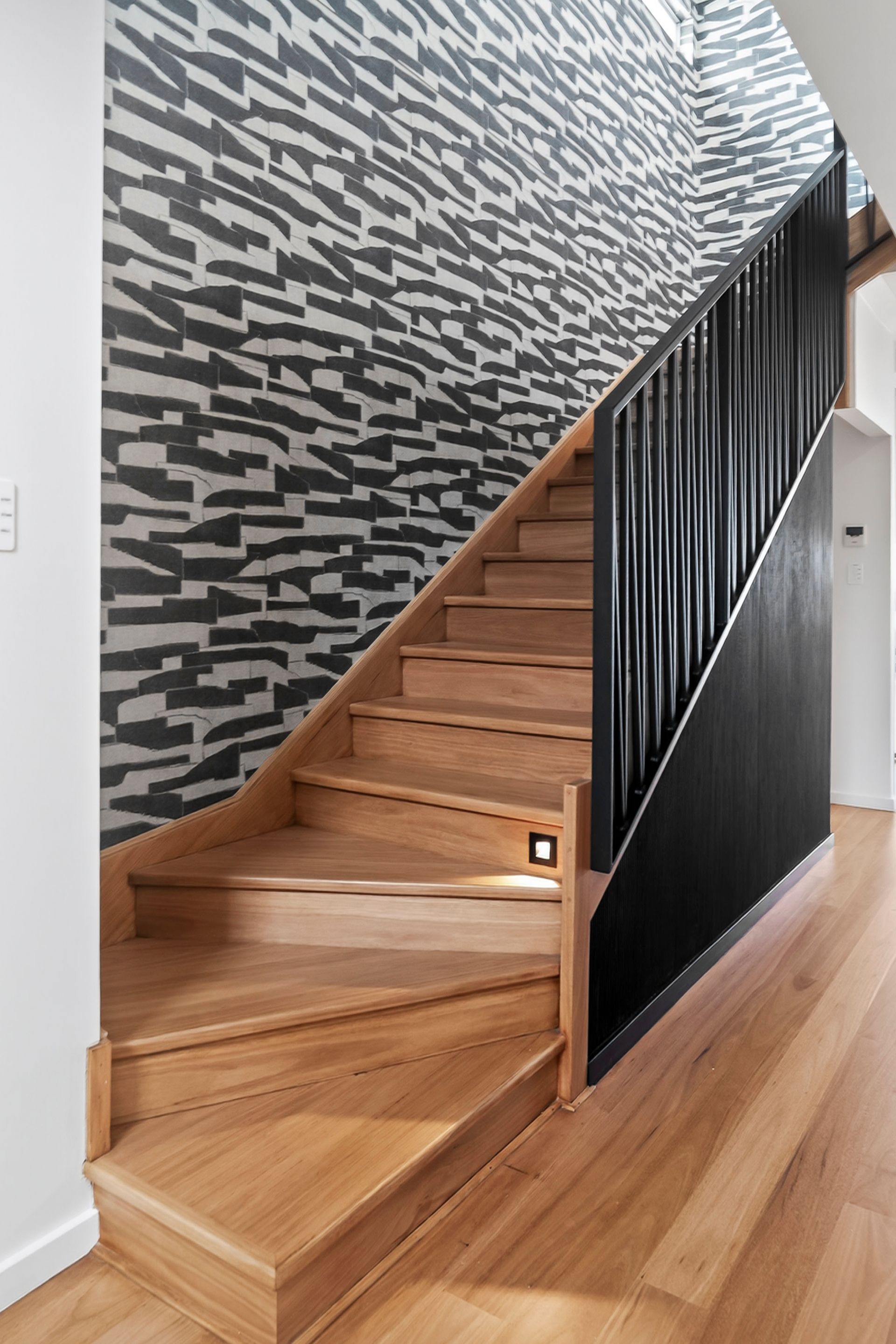 Wooden staircase with patterned wall and black railing. — PK4 Projects in Port Macquarie, NSW