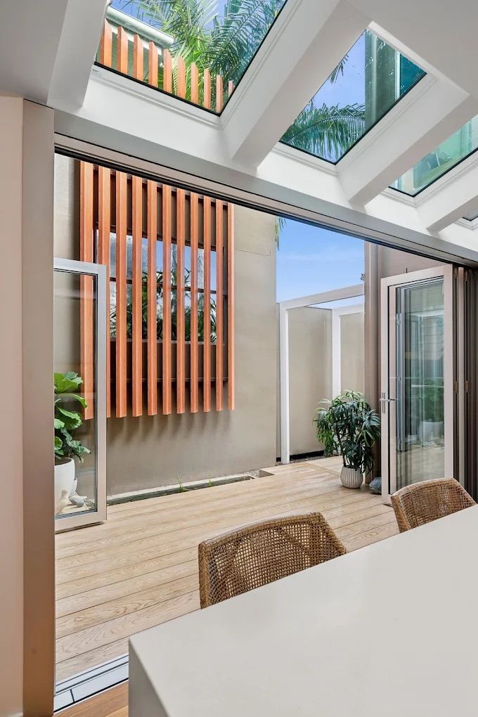 Bright, open interior space with wooden floor and vertical wood slat wall feature. Sliding doors open to patio — PK4 Projects in Port Macquarie, NSW 