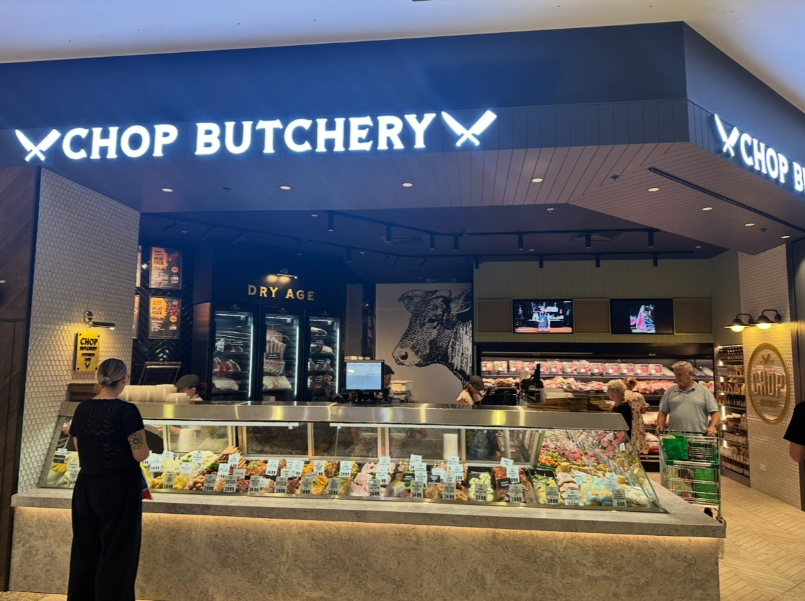 A butcher shop with a counter displaying meat products. A customer and staff member stand near the counter — PK4 Projects in Port Macquarie, NSW