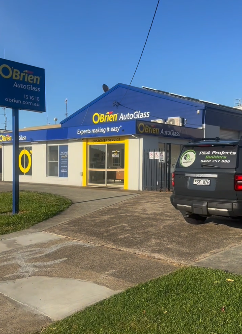 O'Brien AutoGlass building with sign, blue and yellow facade, car parked in front — PK4 Projects in Port Macquarie, NSW