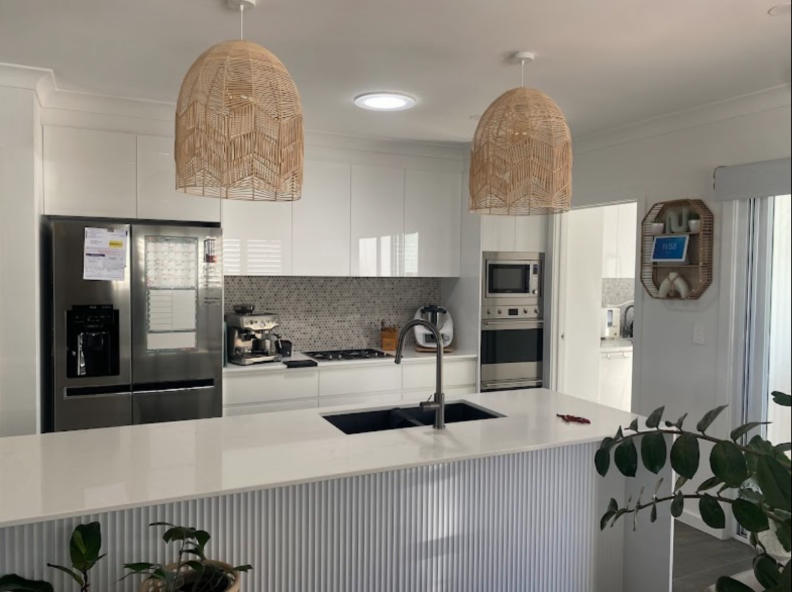 White kitchen with stone countertop, wicker pendant lights, and stainless steel appliances — PK4 Projects in Port Macquarie, NSW