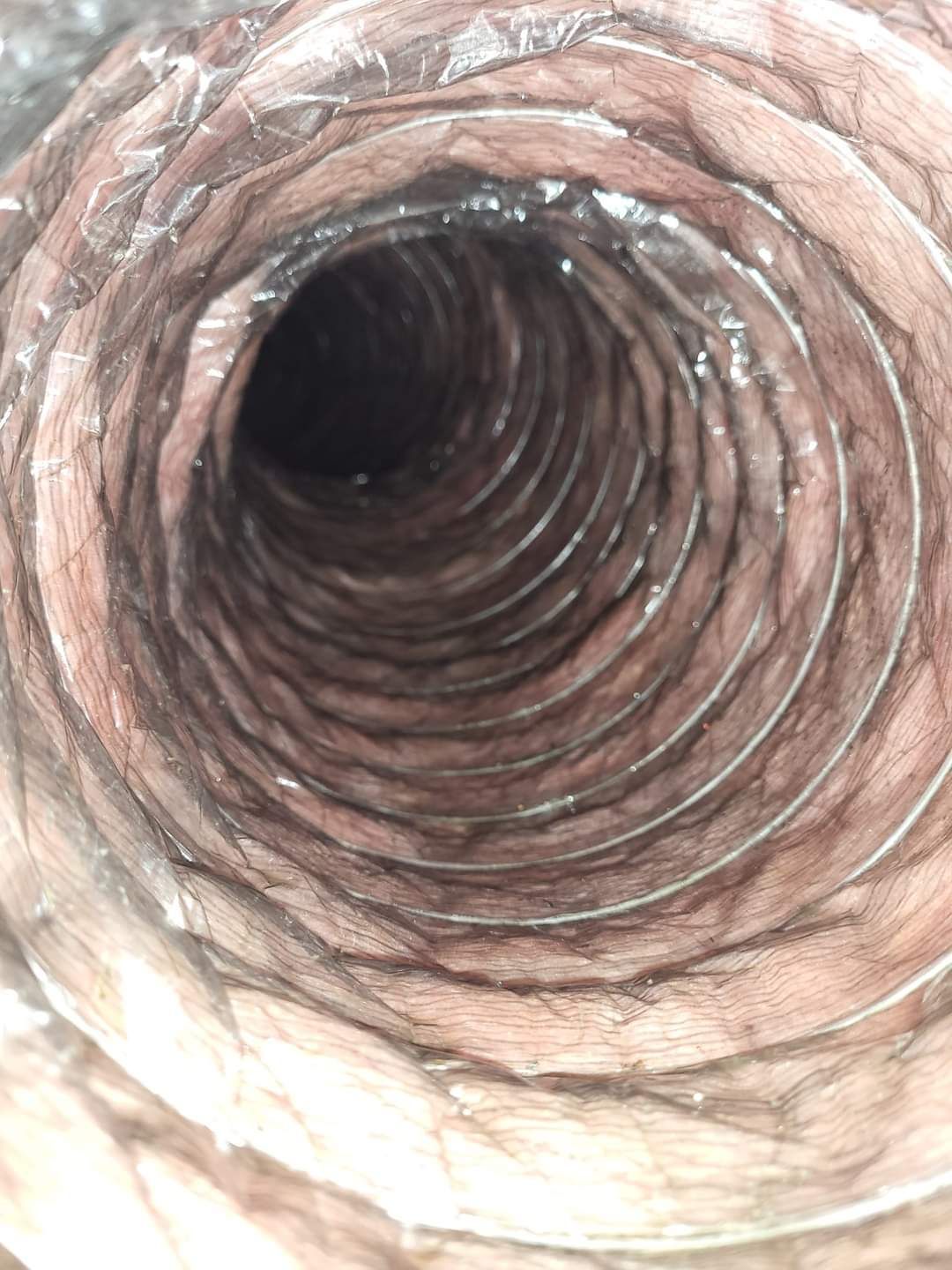 Inside of a spiral metal pipe or duct with rust-colored, ridged walls