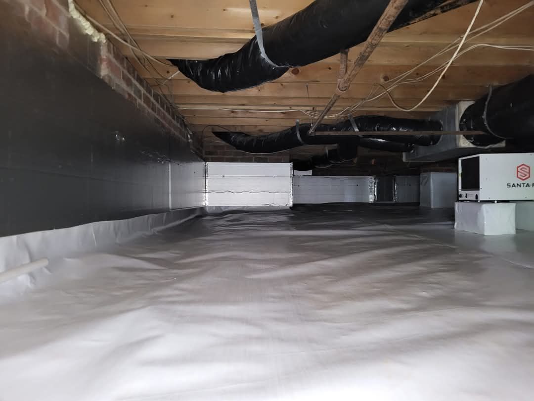 Crawlspace under a floor with plastic sheeting, exposed beams, and ductwork overhead