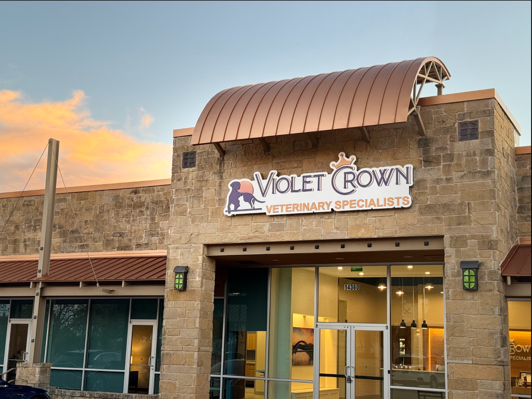 Violet Town storefront at dusk with a stone facade and copper awning