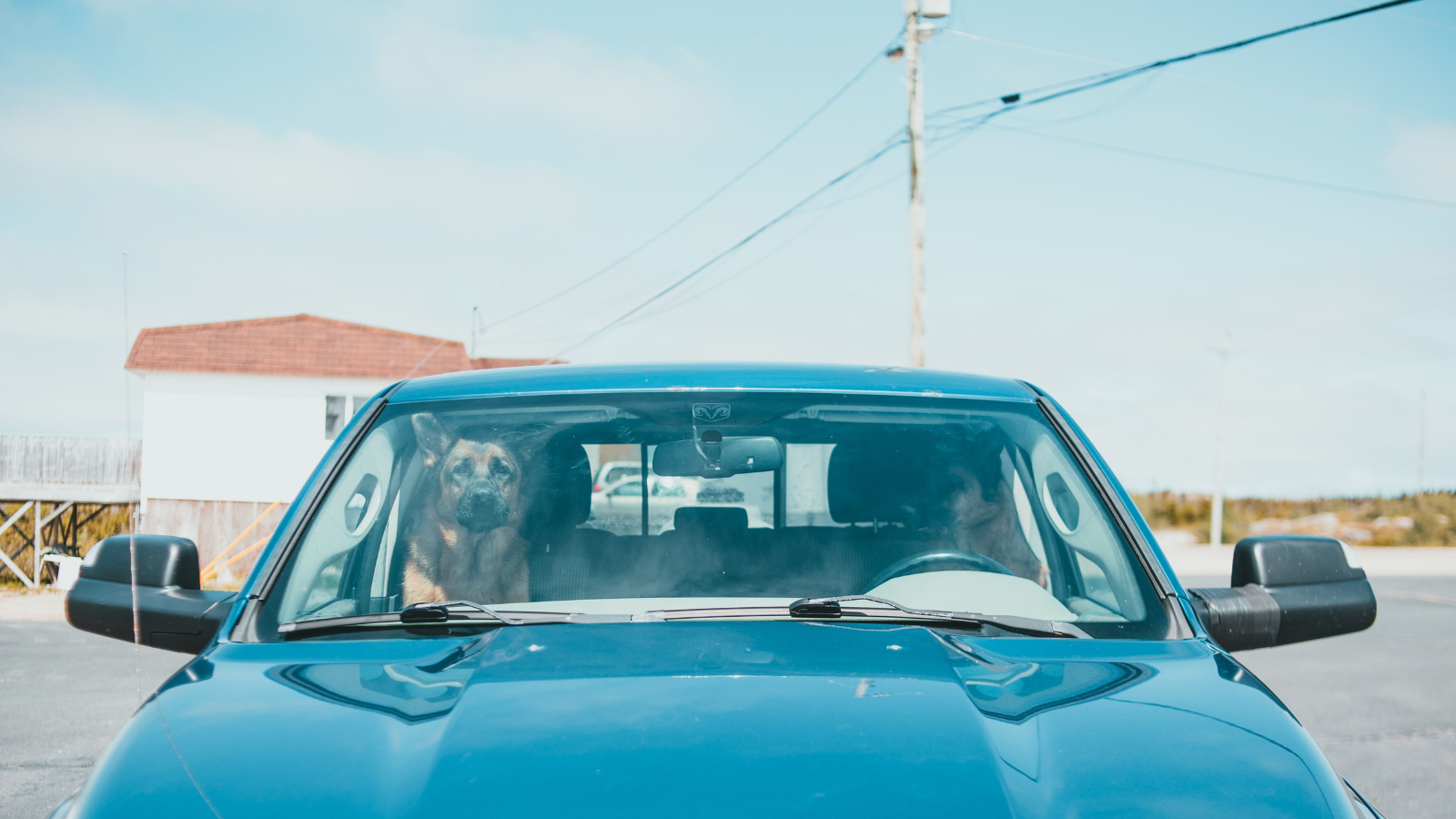 Blue car parked outdoors near a small building under a clear sky