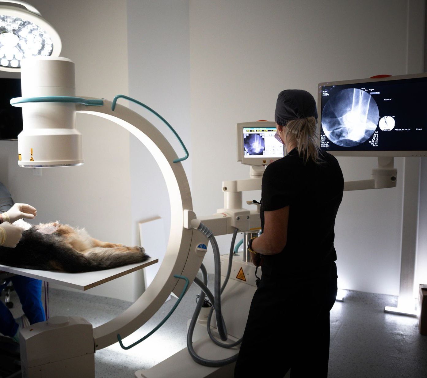 Medical imaging room with a patient on a table and a clinician operating a large C-arm scanner