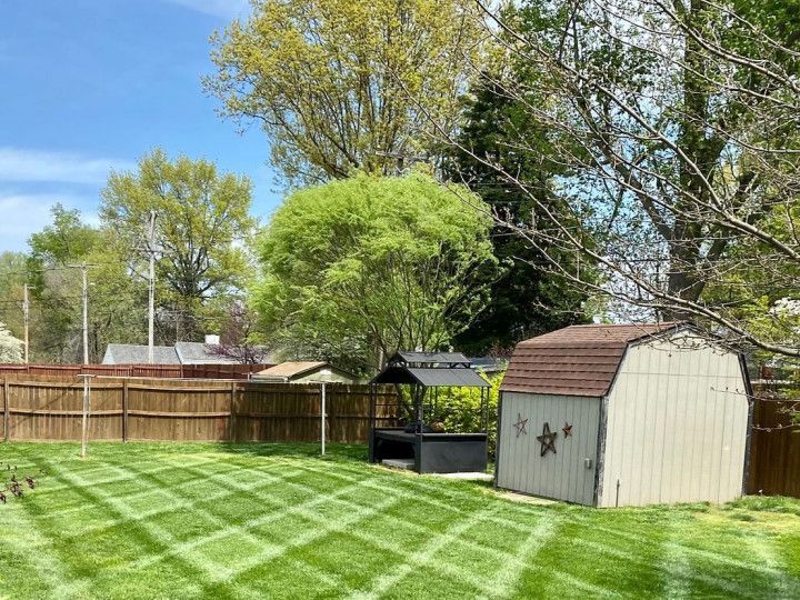 A backyard with a shed , gazebo , and a fence.