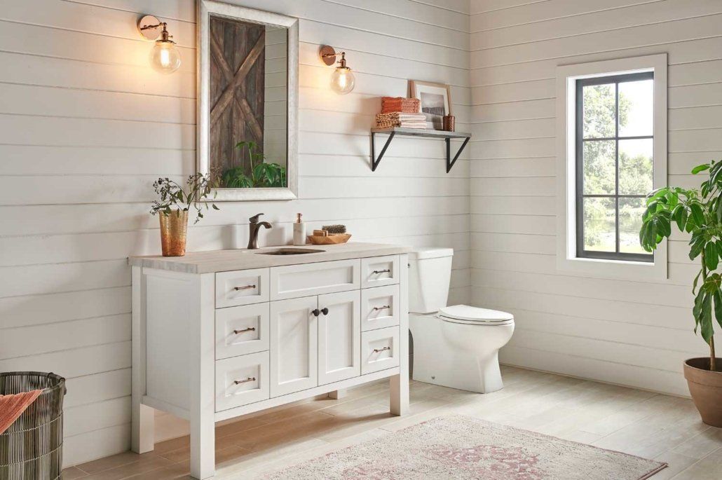 Bright white bathroom with vanity, toilet, wall shelves, and plants in a sunlit minimalist interior