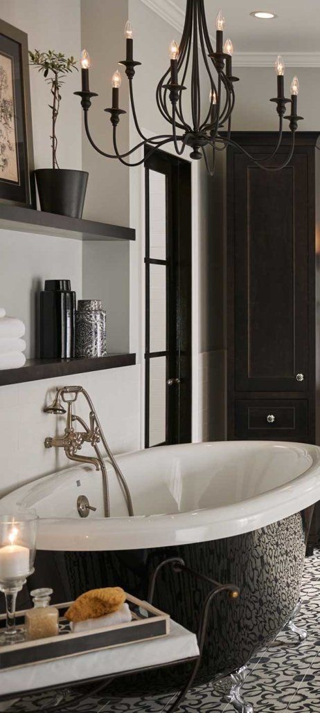 Elegant black-and-white bathroom with a freestanding tub, chandelier, open shelving, and dark cabinet